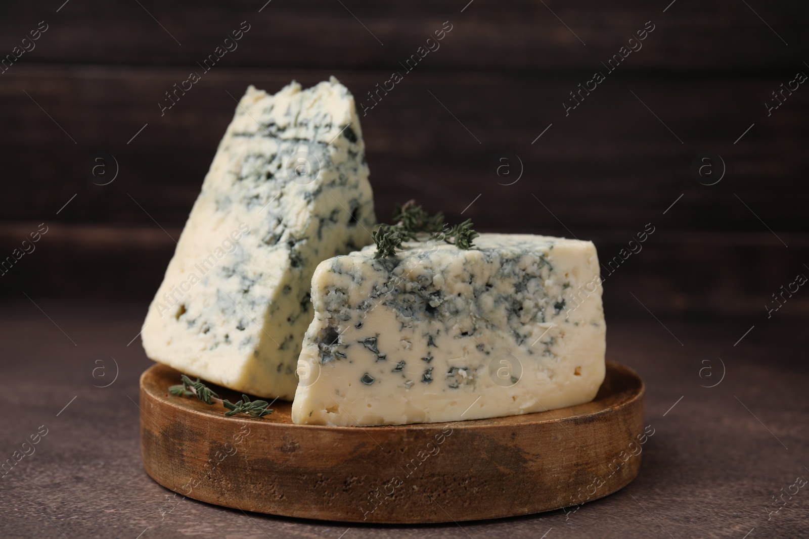 Photo of Tasty blue cheese with thyme on brown table