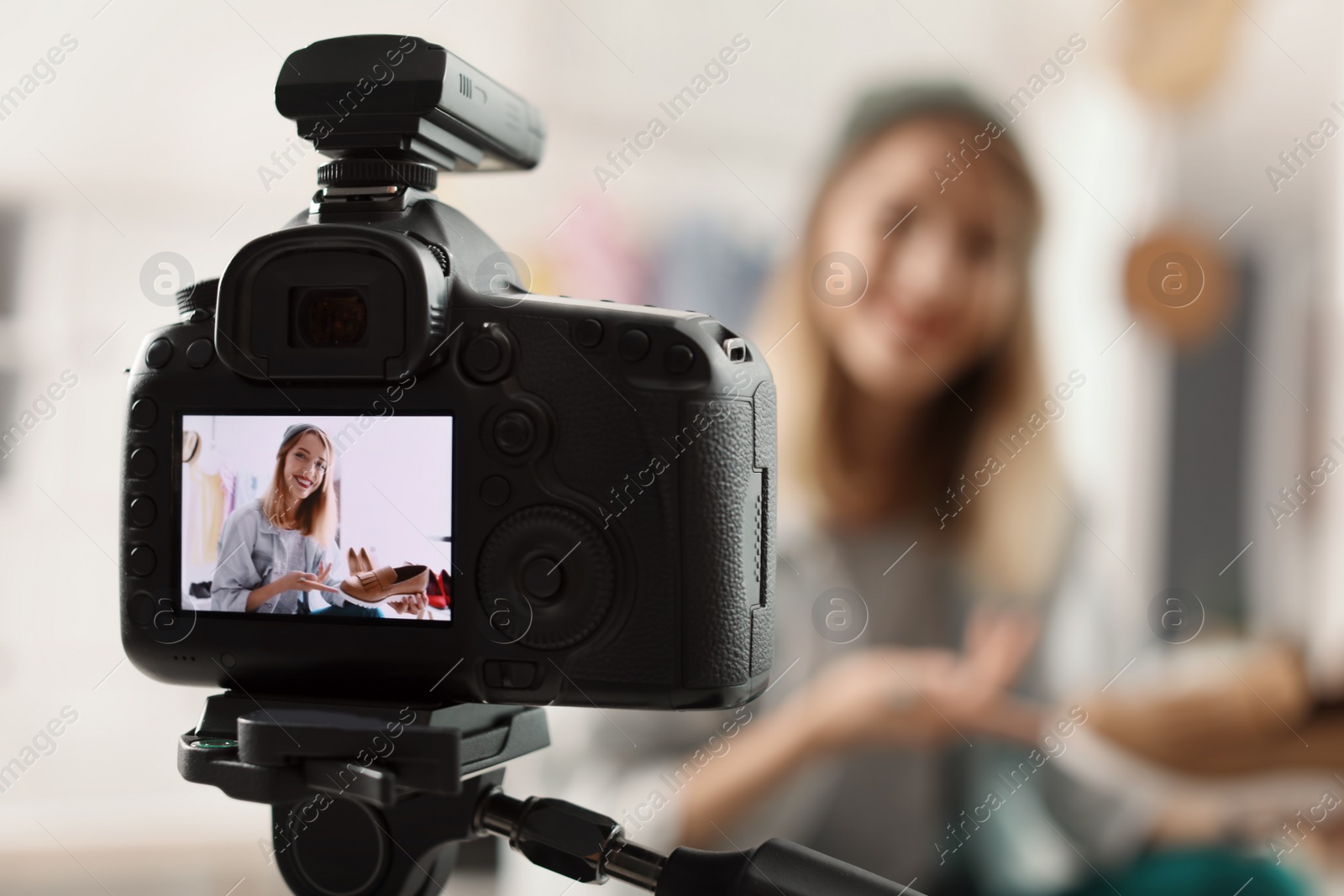 Photo of Fashion blogger recording video indoors, selective focus on camera display. Space for text