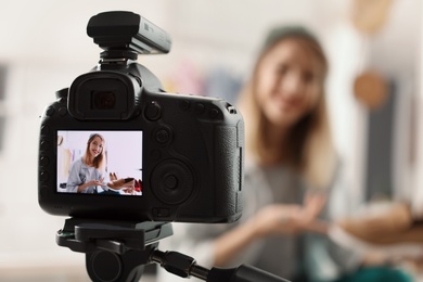 Photo of Fashion blogger recording video indoors, selective focus on camera display. Space for text