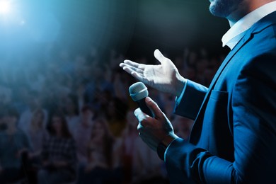 Image of Motivational speaker with microphone performing on stage, closeup