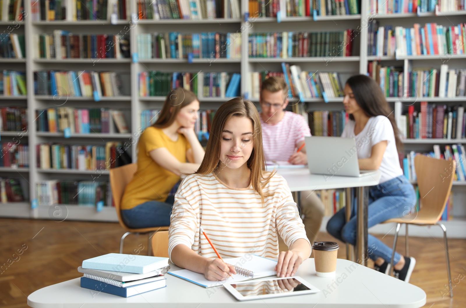 Photo of Young woman studying at table in library