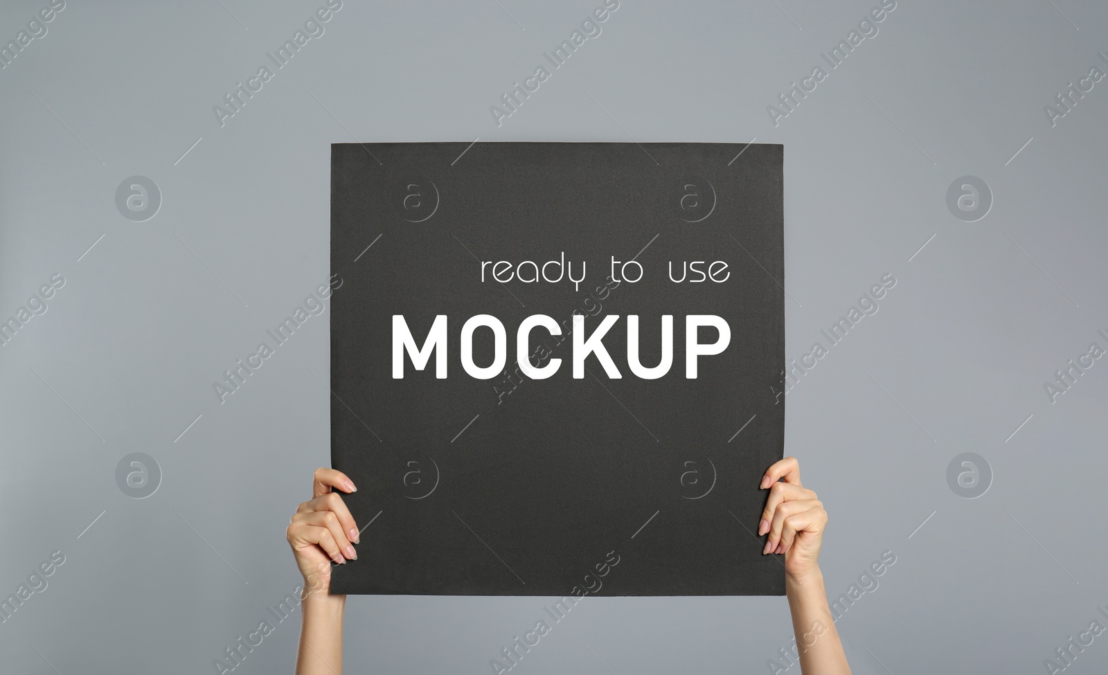 Image of Woman holding black poster with text Mockup Ready To Use on grey background, closeup