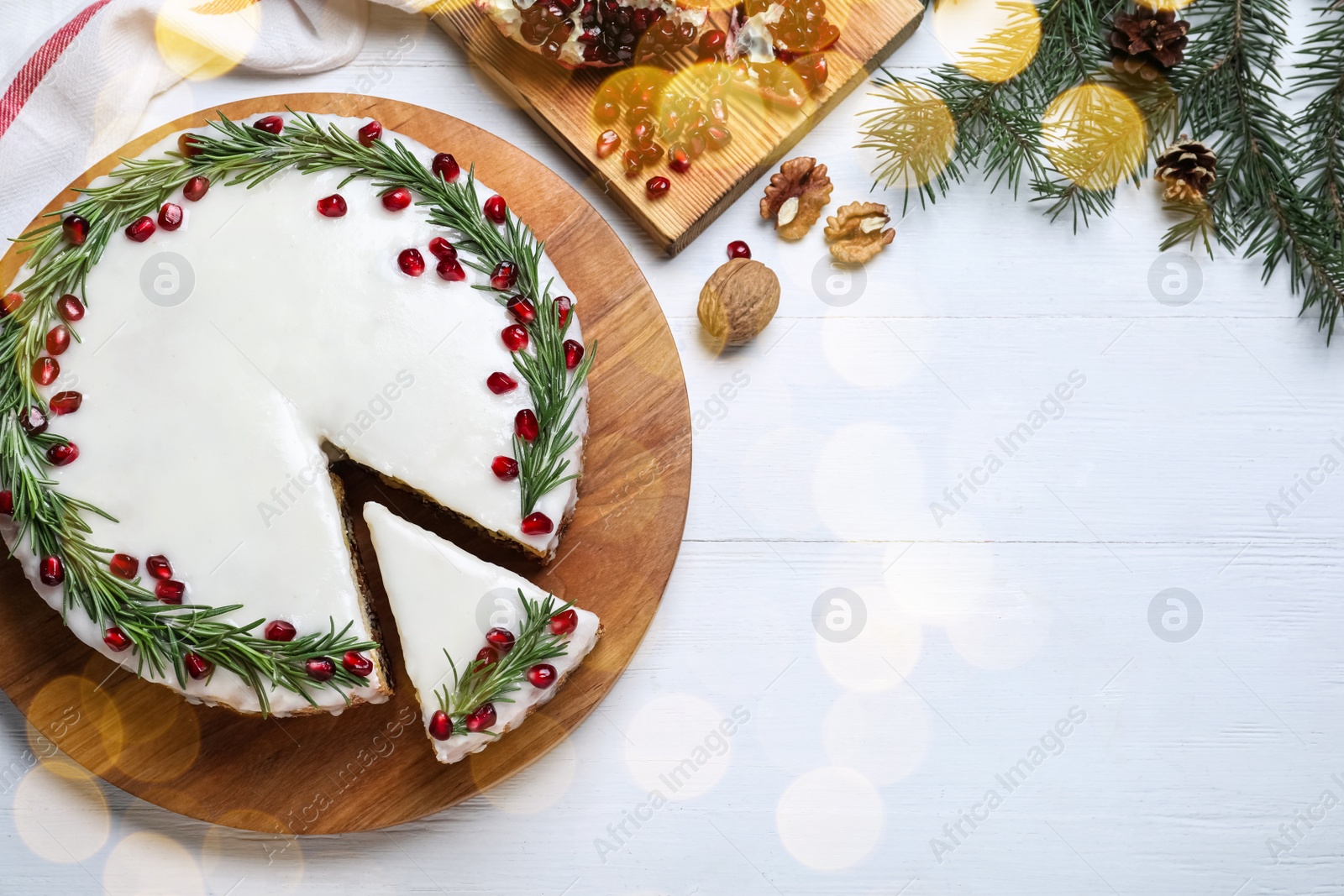 Image of Flat lay composition with traditional Christmas cake on white wooden table, space for text. Bokeh effect