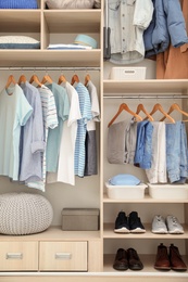 Photo of Stylish clothes, shoes and accessories in large wardrobe closet