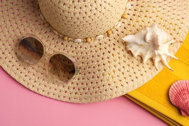 Sunglasses, hat, towel and shells on pink background, flat lay. Beach accessories