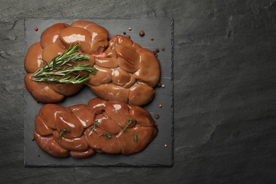 Photo of Fresh raw kidneys with rosemary and thyme on black table, top view. Space for text
