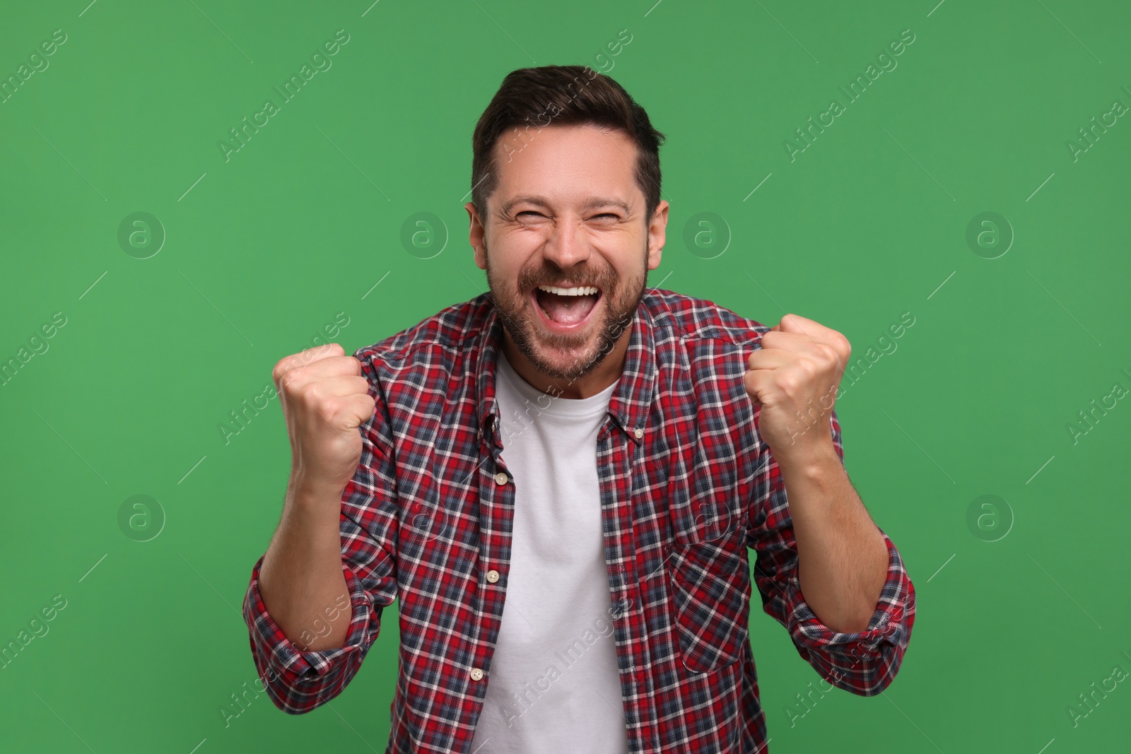 Photo of Emotional sports fan celebrating on green background