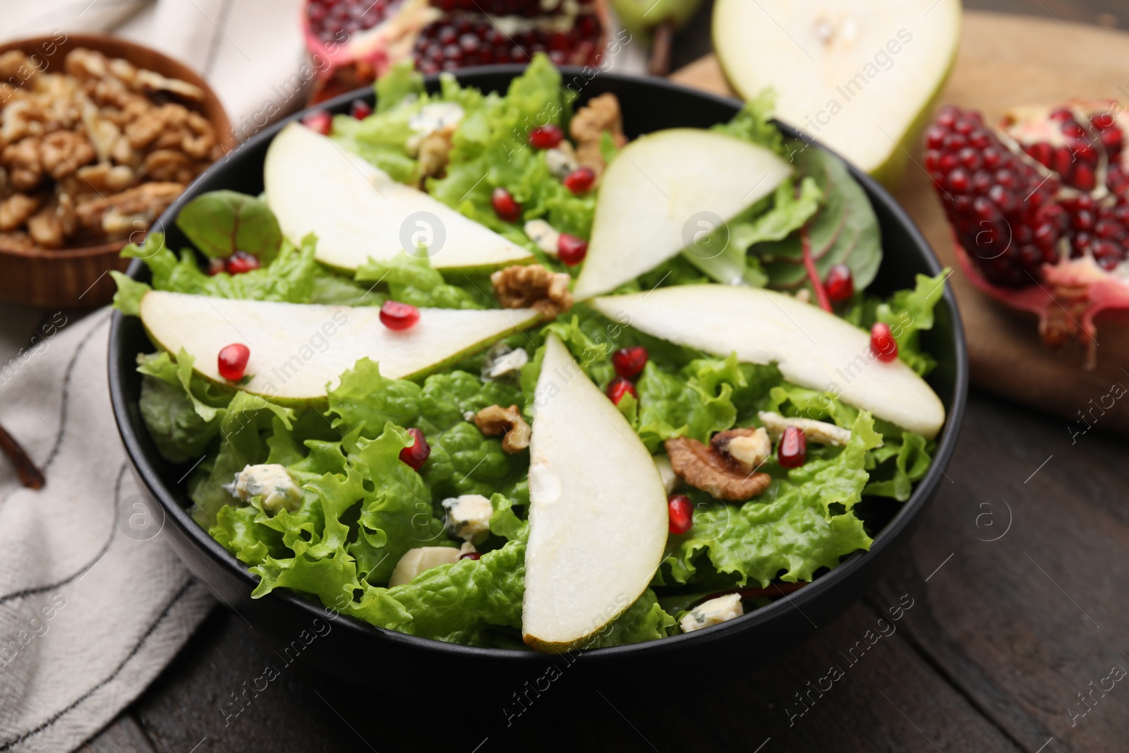 Photo of Delicious pear salad in bowl on wooden table, closeup