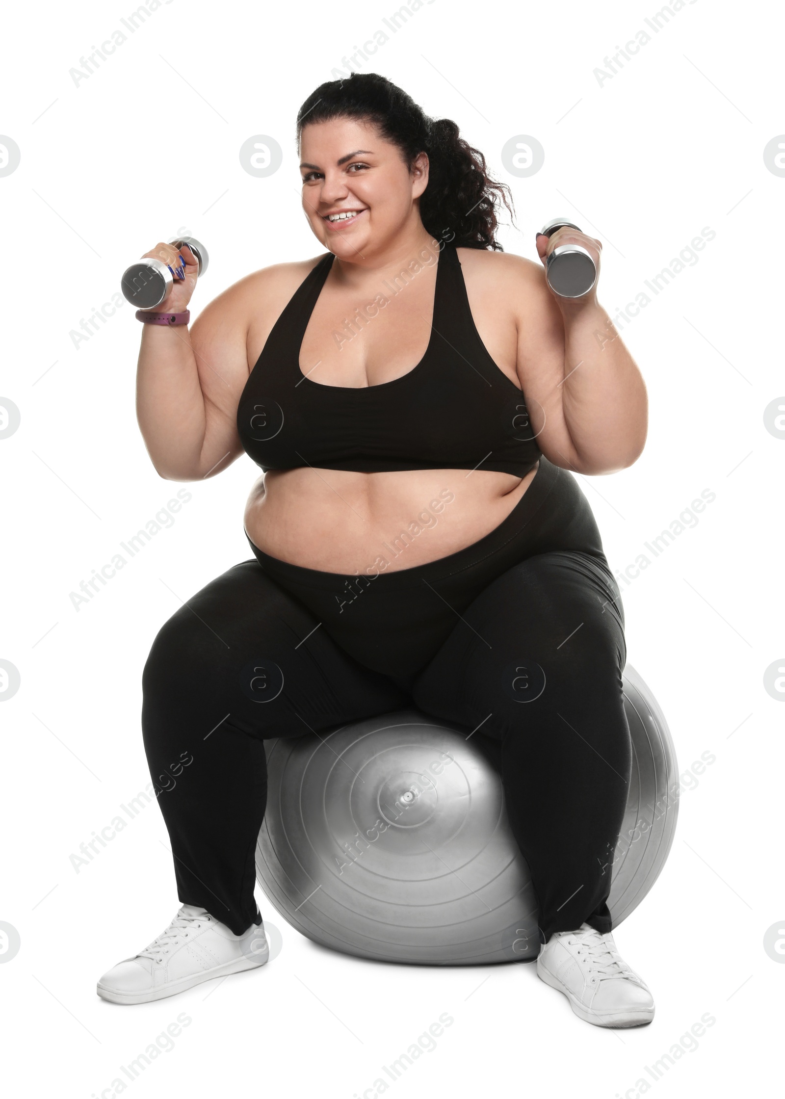 Photo of Overweight woman doing exercise on fit ball with dumbbells against white background