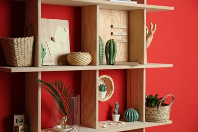 Stylish wooden shelves with decorative elements on red wall