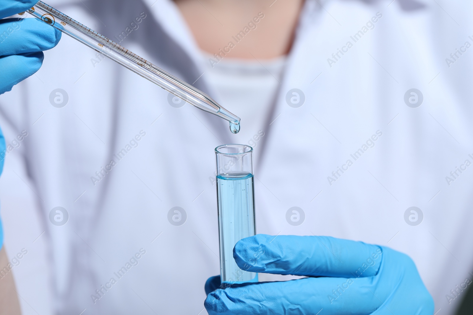 Photo of Scientist dripping liquid from pipette into test tube, selective focus