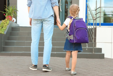 Photo of Young father taking his little child to school outdoors