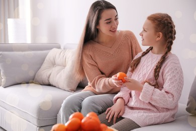 Photo of Happy girls with fresh tangerine sitting on sofa at home