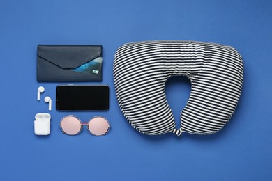 Photo of Flat lay composition with striped travel pillow and smartphone on blue background