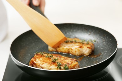 Chef cooking delicious meat with thyme in frying pan indoors, closeup