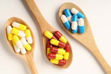 Photo of Antibiotic pills and spoons on white background, flat lay