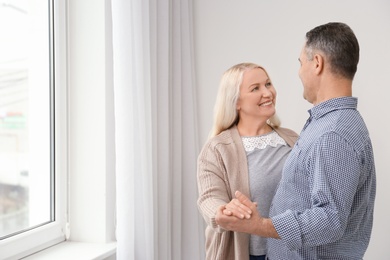 Photo of Happy senior couple near window at home