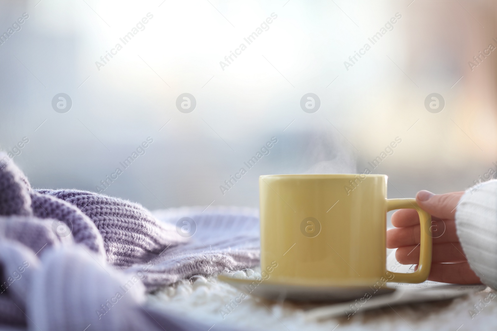 Photo of Woman with cup of coffee and newspaper near window in morning, closeup. Space for text
