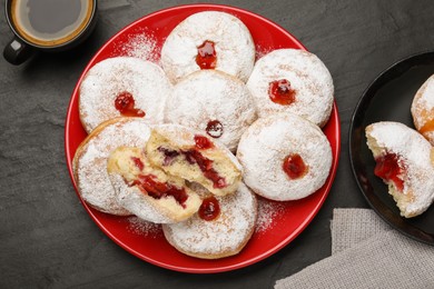 Delicious jelly donuts served with coffee on black table, flat lay