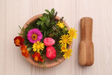 Photo of Mortar with pestle and beautiful fresh flowers on wooden table, top view