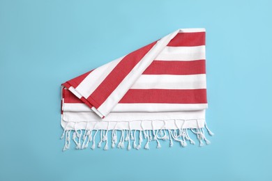 Photo of Folded striped beach towel on light blue background, top view