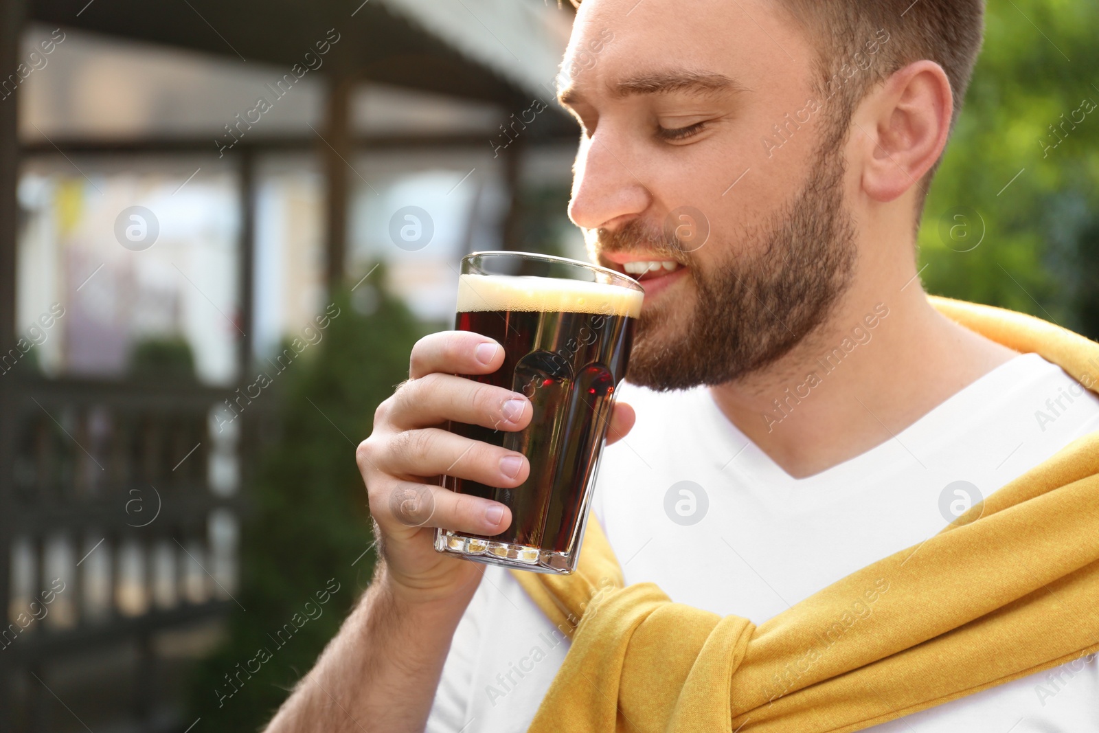 Photo of Handsome man with cold kvass outdoors. Traditional Russian summer drink