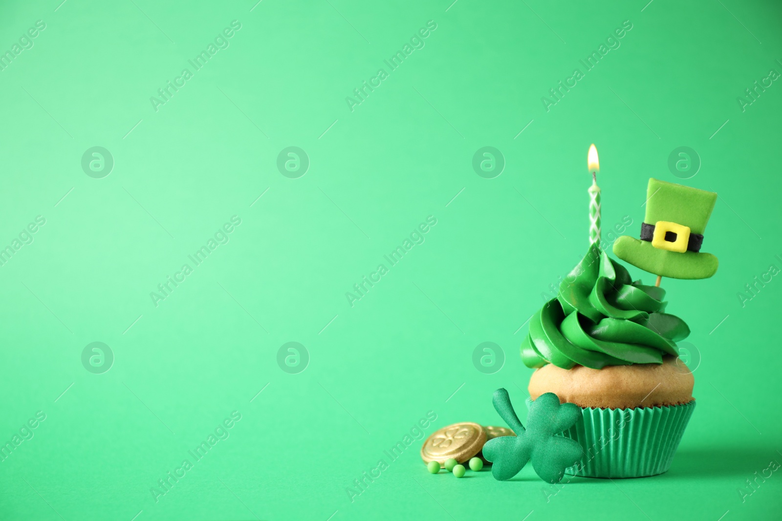 Photo of Decorated cupcake on green background, space for text. St. Patrick's Day celebration