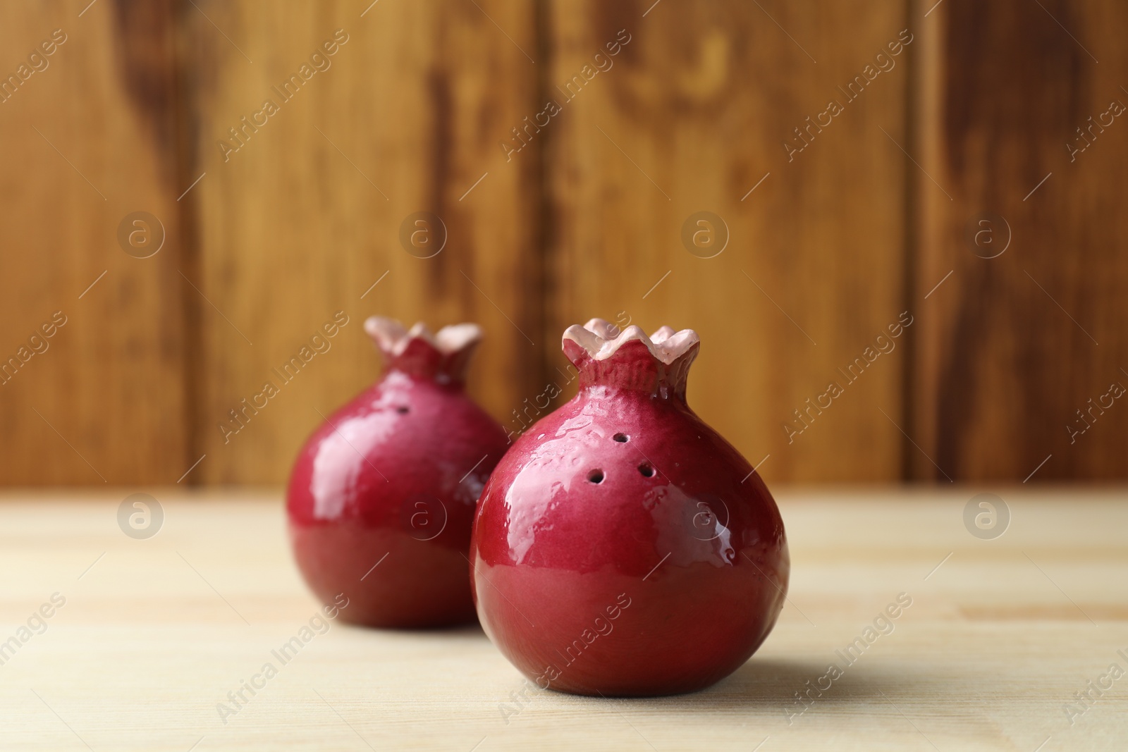Photo of Pomegranate shaped salt and pepper shakers on light wooden table