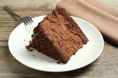 Photo of Piece of delicious chocolate truffle cake and fork on wooden table, closeup