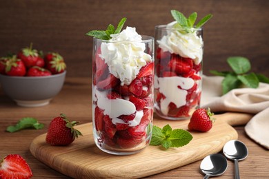 Photo of Delicious strawberries with whipped cream served on wooden table