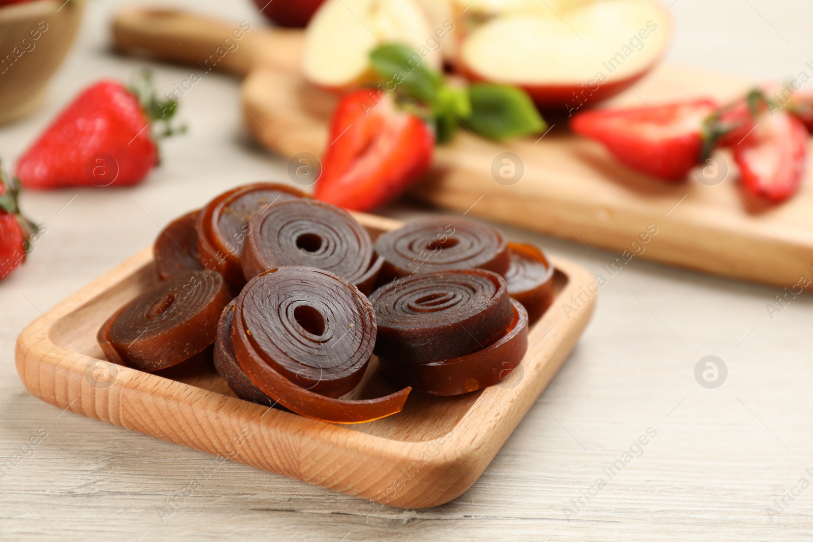 Photo of Composition with delicious fruit leather rolls on white wooden table. Space for text