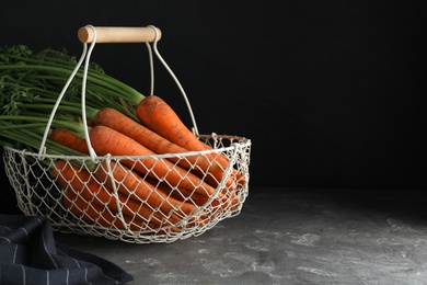 Photo of Basket with raw carrots on grey table. Space for text