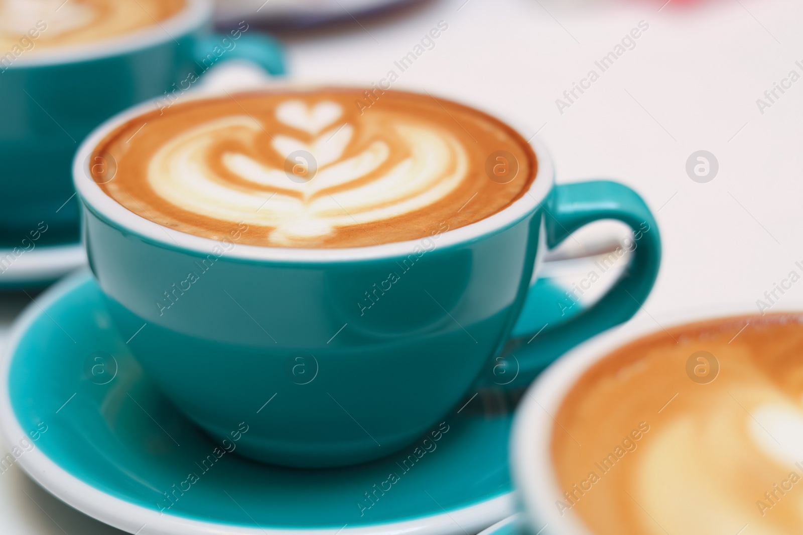 Photo of Cups of aromatic coffee on beige background, closeup