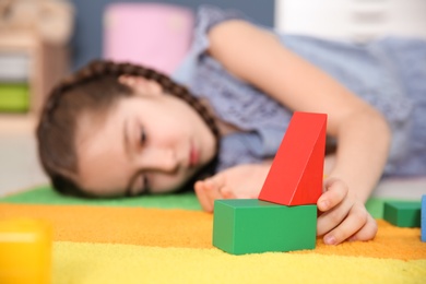 Photo of Little girl with autistic disorder playing at home, closeup of cubes