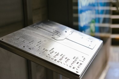 Photo of Silver stand with Braille text and building plan indoors, closeup