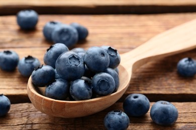 Photo of Spoon with tasty fresh blueberries on wooden table, closeup