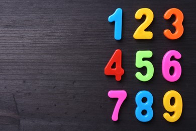 Photo of Colorful numbers on dark wooden school desk, flat lay. Space for text