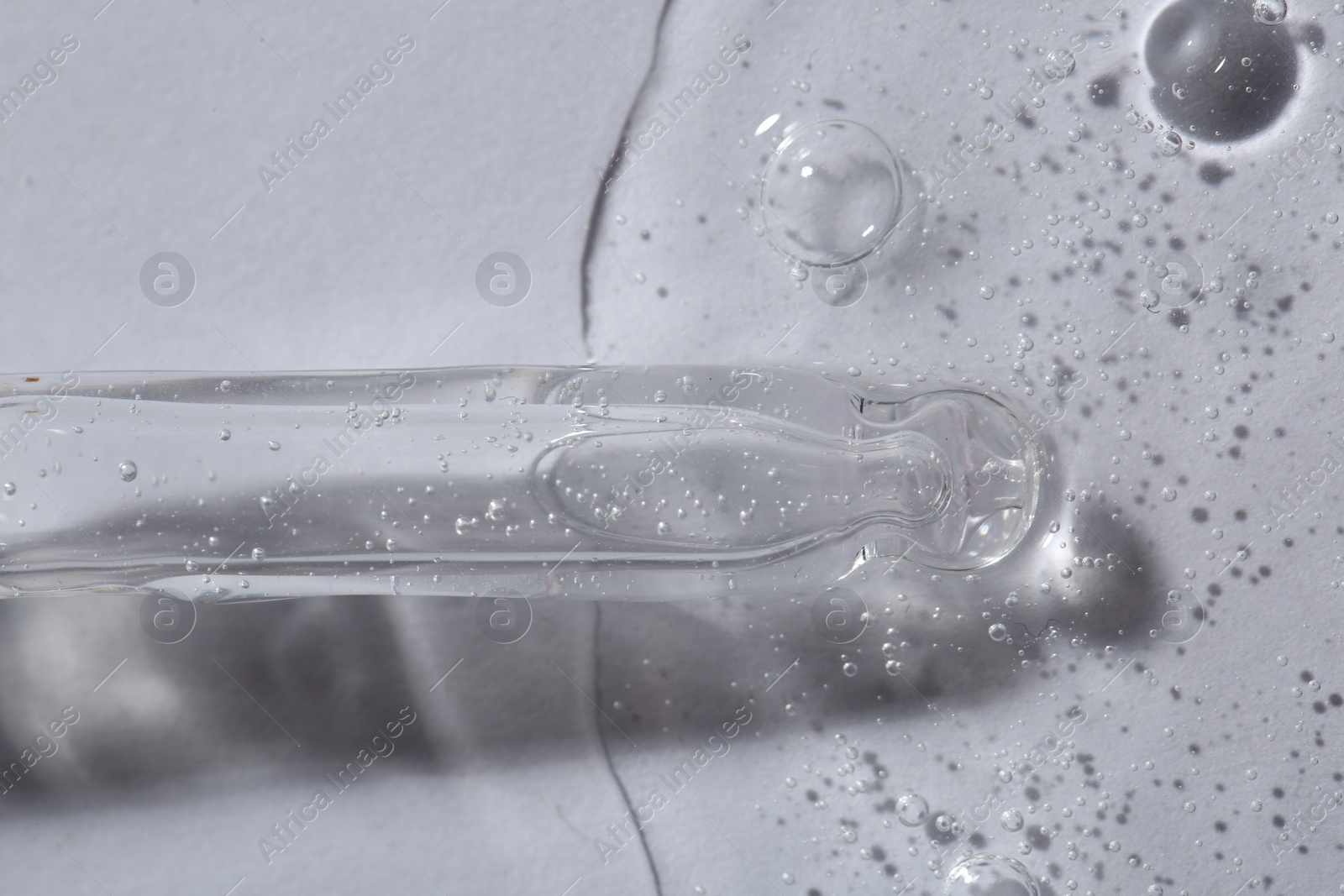 Photo of Pipette with cosmetic serum on white background, macro view