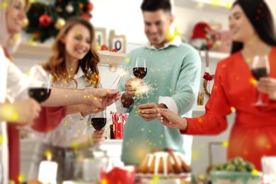 Image of Happy family and friends with sparklers celebrating Christmas Eve at festive dinner indoors. Bokeh effect