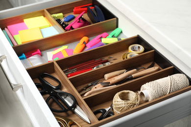 Photo of Sewing accessories and stationery in open desk drawer indoors