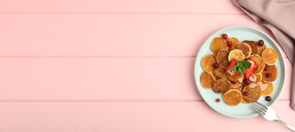 Image of Cereal pancakes with berries on pink wooden table, flat lay with space for text. Banner design