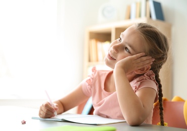 Photo of Cute little child daydreaming at desk in classroom. Elementary school
