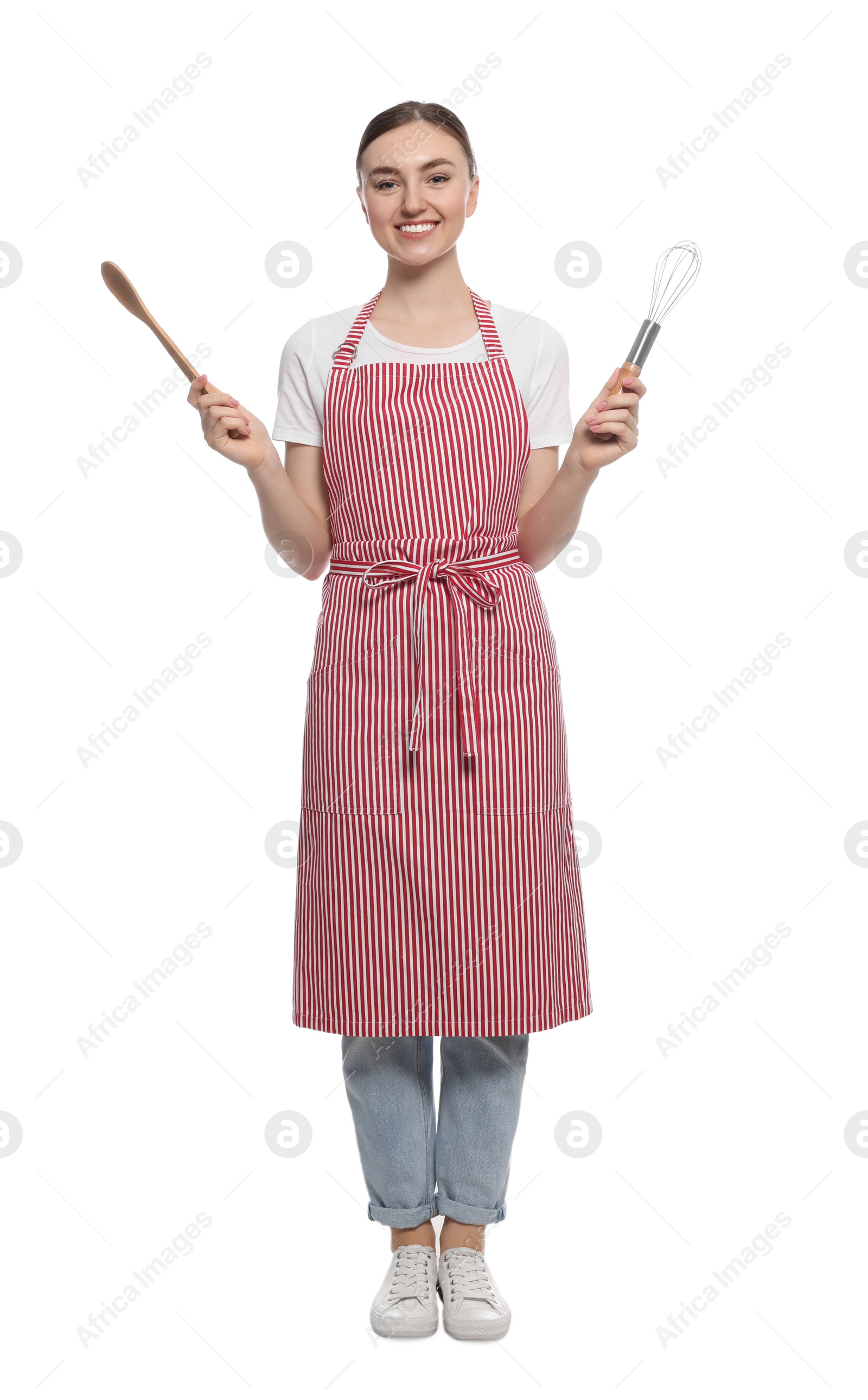 Photo of Beautiful young woman in striped apron with kitchen tools on white background