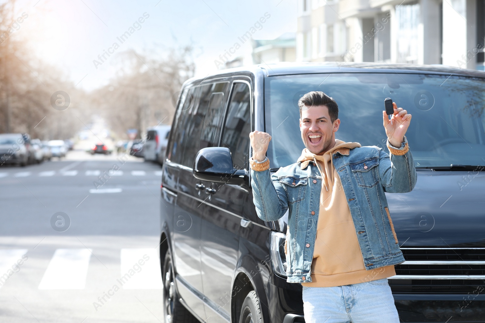 Photo of Excited man with key near car on city street. Buying new auto