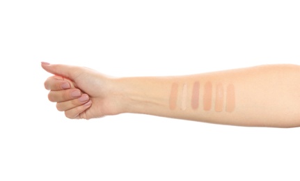 Photo of Woman testing different shades of liquid foundation on her hand against white background, closeup