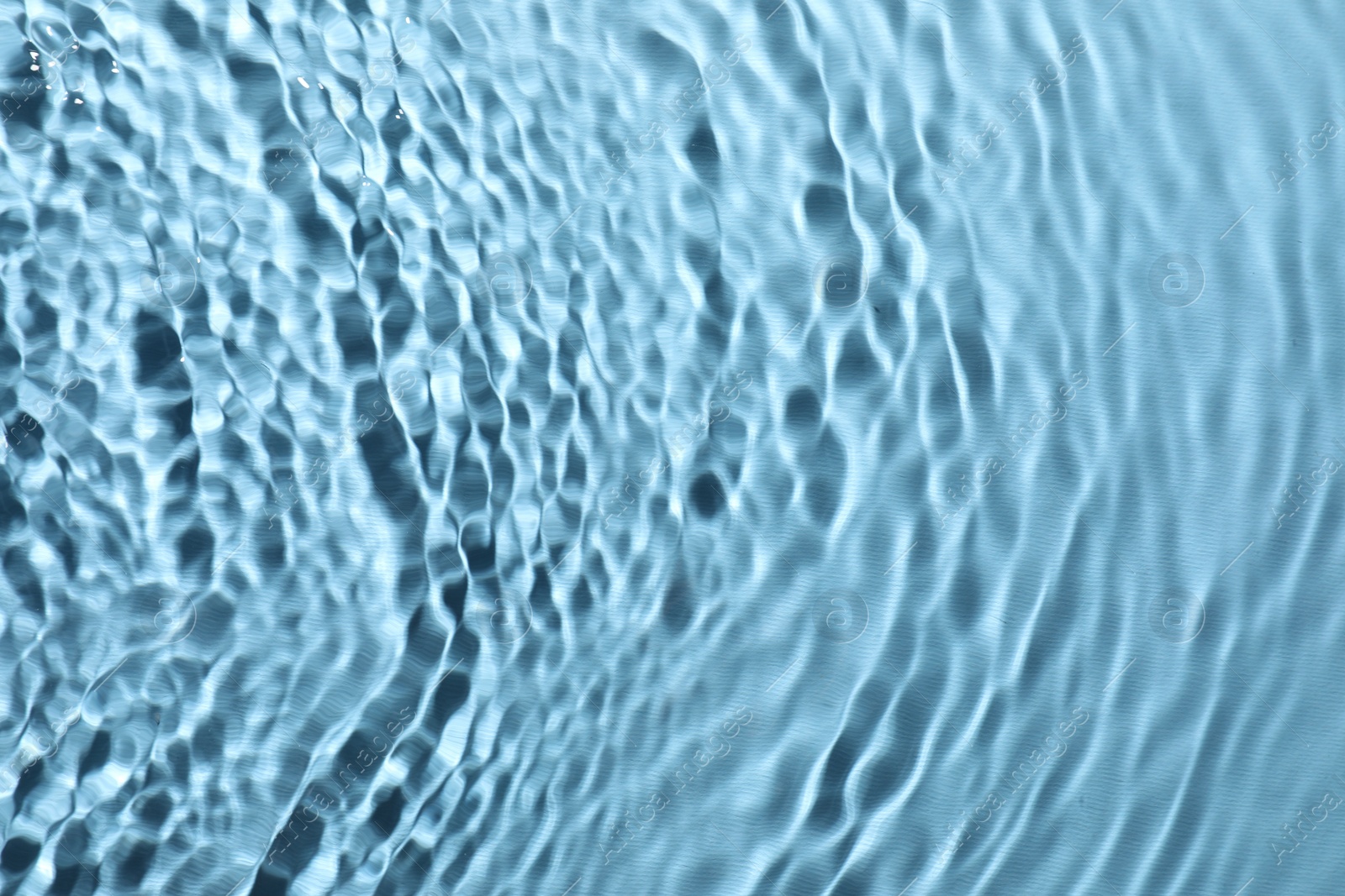 Photo of Rippled surface of clear water on light blue background, top view