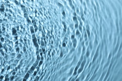 Rippled surface of clear water on light blue background, top view