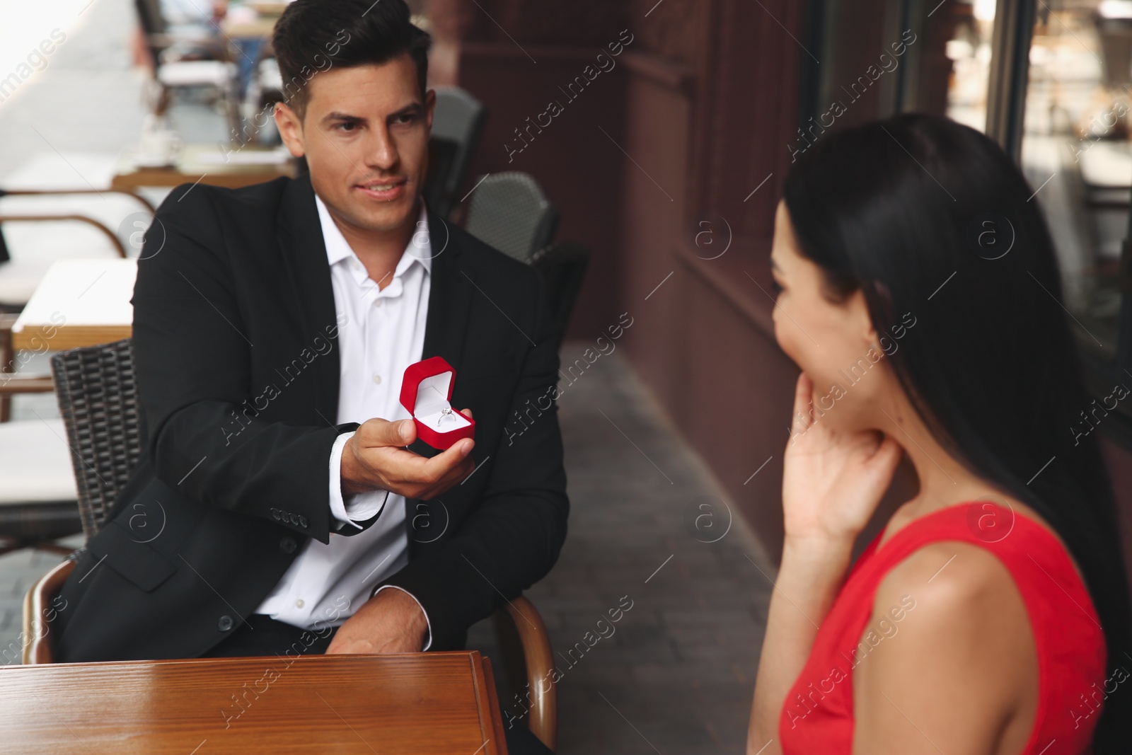 Photo of Man with engagement ring making proposal to his girlfriend in outdoor cafe