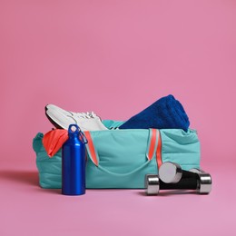 Photo of Blue gym bag and sports accessories on pink background