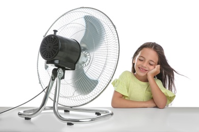 Photo of Little girl enjoying air flow from fan on white background. Summer heat